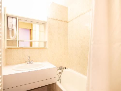a bathroom with a sink and a tub and a mirror at Vacancéole - Résidence Le Sappey - Doucy in La Léchère