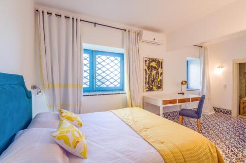 a bedroom with a bed and a desk and a window at La Demeure in Sidi Bou Saïd