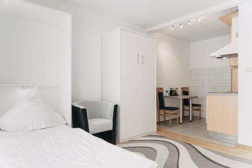 a white bedroom with a bed and a kitchen at Apartment-EG-05 in Darmstadt
