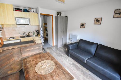 a living room with a couch and a kitchen at Au Pied des Pistes B48, Chaleureux studio 4 pers, balcon plein SUD, DRAPS NON COMPRIS in Saint-Jean-dʼAulps