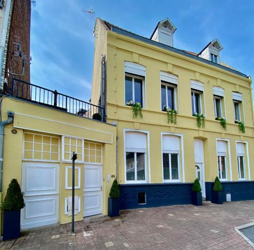 een geel huis met witte garagedeuren bij N°2 L'épicéa - Appart Hôtel La Maison Sévigné in Béthune