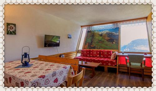 um quarto com uma mesa, um sofá e uma janela em les 3 marmottes - Les Arolles em Bourg-Saint-Maurice