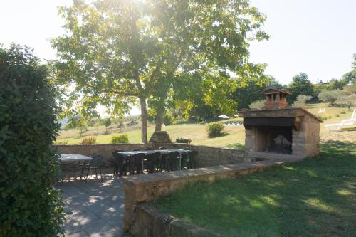 a patio with tables and chairs and a stone fireplace at Villa al Confine by Mmega in Calzolaro