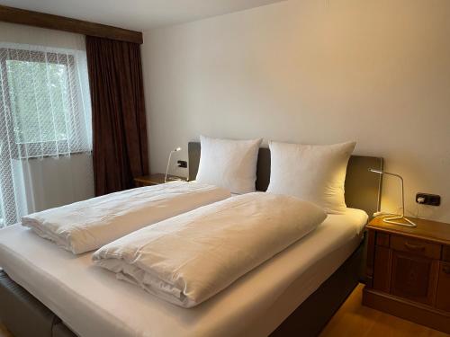 a bedroom with two beds with white sheets and a window at Appartement Oberlacken in Sankt Johann in Tirol