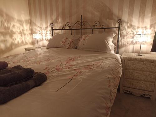 a bedroom with a large bed with two lamps at Comfortable Billericay Home in Billericay