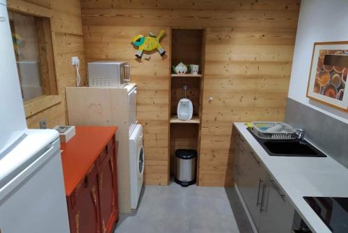 a small kitchen with wooden walls and a refrigerator at Le Domaine des Fleurs - Appartement La Gentiane in Gérardmer