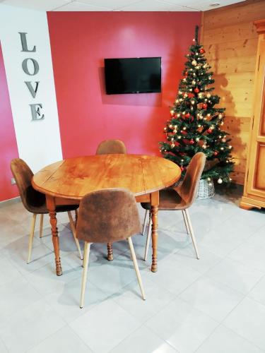 a wooden table with chairs and a christmas tree at Le Domaine des Fleurs - Appartement La Gentiane in Gérardmer