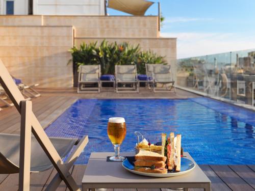 a table with a plate of food and a glass of beer at H10 Art Gallery 4* Sup in Barcelona