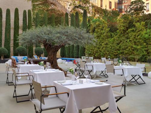 a group of tables with white chairs and a tree at H10 Art Gallery 4* Sup in Barcelona