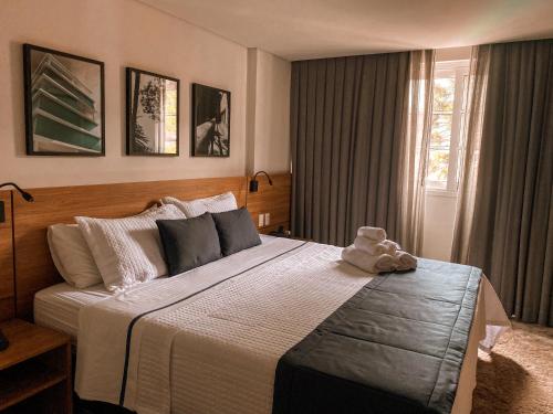 a bedroom with a large bed with a teddy bear on it at Apart-hotel Granja Brasil Itaipava in Itaipava