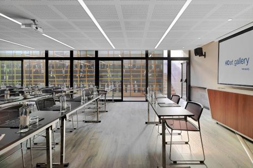 a conference room with tables and chairs and a screen at H10 Art Gallery 4* Sup in Barcelona