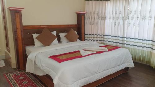 a bedroom with a large bed with white sheets at London House Resort in Birātnagar