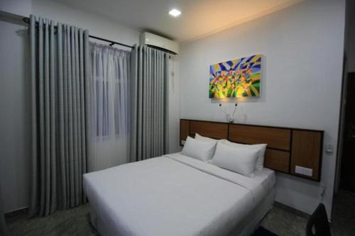 Un dormitorio con una cama blanca y una pintura en la pared en Serenity Tissa, en Tissamaharama