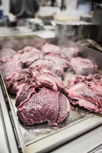 a bunch of meat is being cooked on a pan at Verwöhn-Wellnesshotel Walserhof in Hirschegg