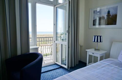 a bedroom with a bed and a view of the ocean at Parkhotel Seeblick in Warnemünde