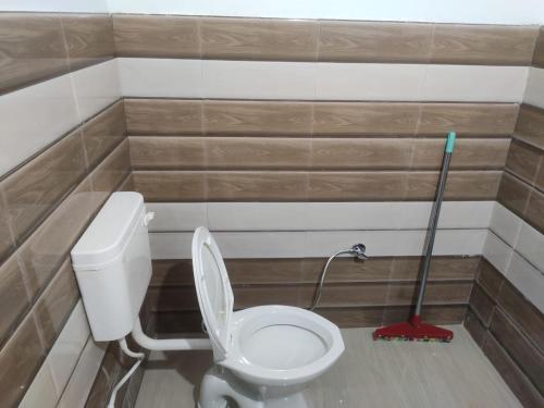 a bathroom with a toilet and a mop in it at HimWanderer Camps & Cottages Pangot in Nainital