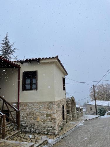 a house with snow falling on the side of it at St. John Traditional House in Áyios Ioánnis