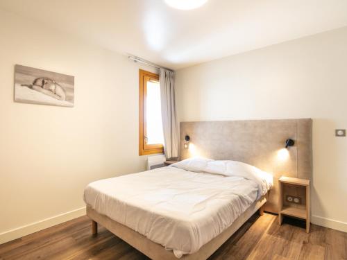 a bedroom with a white bed with a window at Vacancéole - Résidence Le Beauregard in La Léchère