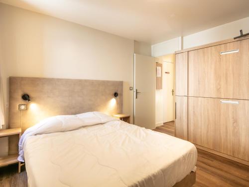 a bedroom with a large bed and a wooden cabinet at Vacancéole - Résidence Le Beauregard in La Léchère