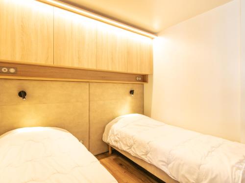 a bedroom with two beds and wooden cabinets at Vacancéole - Résidence Le Beauregard in La Léchère