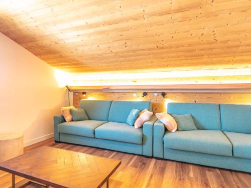 a blue couch in a room with a wooden ceiling at Vacancéole - Résidence Le Beauregard in La Léchère