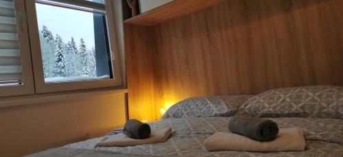 a bedroom with two towels on a bed with a window at Bjelašnica Vukov Vis 09 - apartment with a bedroom in Bjelašnica