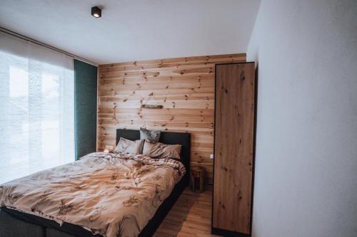 a bedroom with a bed with a wooden wall at Haus Bergzauber in Ramsau am Dachstein