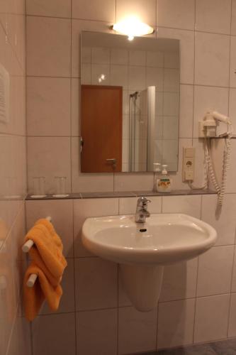 a white bathroom with a sink and a mirror at Zur Querensteder Mühle in Bad Zwischenahn