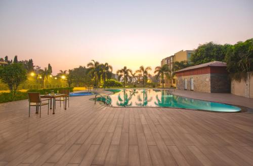 a swimming pool with a table and chairs and a building at Lemon Tree Hotel Baddi in Baddi