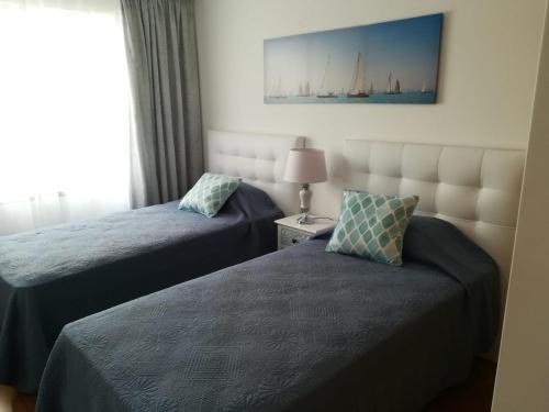 um quarto de hotel com duas camas e uma janela em Tamariz Flat em Santa Cruz - Madeira