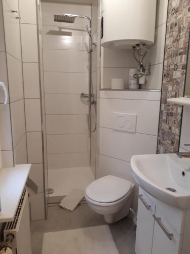 biała łazienka z toaletą i umywalką w obiekcie Ferienwohnung 2 bei Familie Saupe w mieście Schaprode