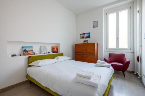 sypialnia z łóżkiem i czerwonym krzesłem w obiekcie Loft Moderno in Dateo w Mediolanie