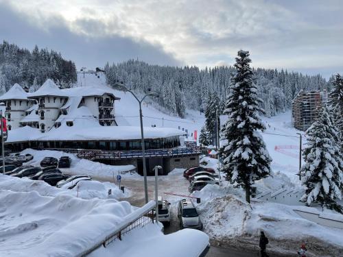 a snow covered ski lodge with cars parked in the snow at Olimpijska kuca 202 in Jahorina