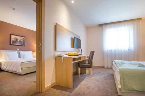 a hotel room with a bed and a desk with a computer at Etno Naselje Vrdnička kula in Vrdnik