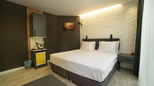 a bedroom with a white bed with a brick wall at Estera Hotel Silent in Antalya