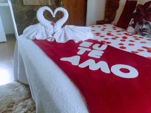 a bed with a red and white blanket with two swans at Chales Boa Vista in Monte Verde