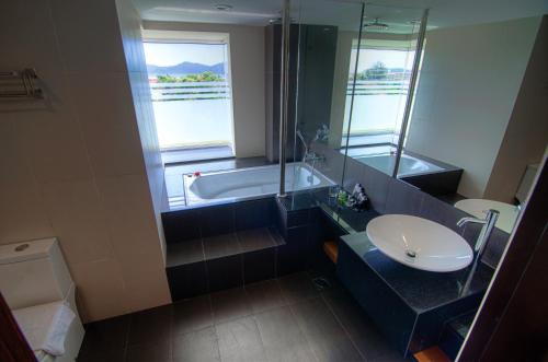 ein Badezimmer mit einer Badewanne, einem Waschbecken und einem Spiegel in der Unterkunft C'haya Hotel in Kota Kinabalu