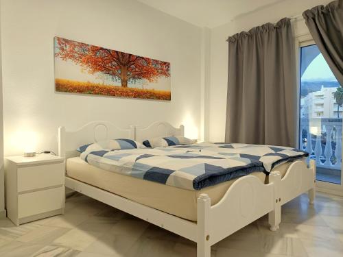 a bedroom with a bed with a tree painting on the wall at Apartamentos StarNerja en Stella Maris in Nerja