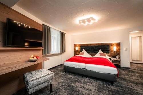 a bedroom with a red and white bed and a chair at Hotel Tradizio in Mittelberg