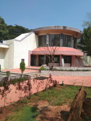 a large building with a pink roof and a yard at KSTDC Hotel Mayura Pavithra Yediyur in Kunigal