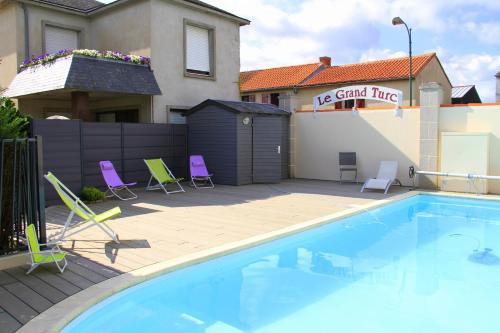 une piscine avec des chaises et une maison dans l'établissement Logis Hotel Restaurant Le Grand Turc, à LʼOie