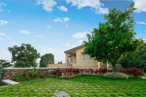 a house with a green lawn and a tree at SaffronStays Forest Trails, Pawna - pool villa with forest views in Āmbavna