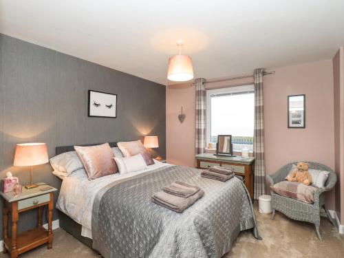 a bedroom with a bed and a chair and a window at Solway View in Wigton