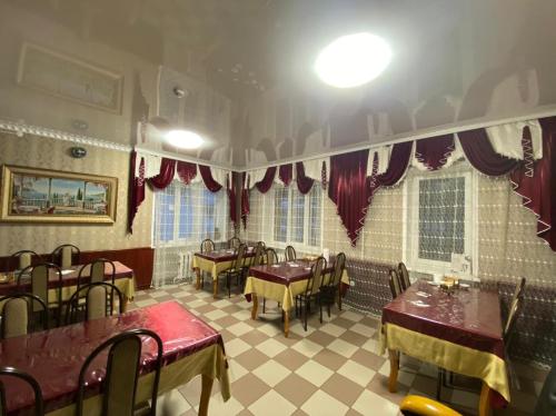 a restaurant with tables and chairs and red curtains at Hotel Moscow in Dombay