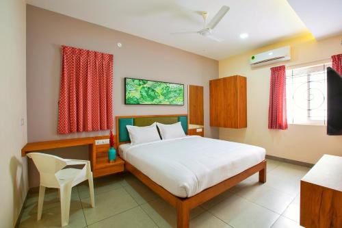 a bedroom with a bed and a desk and a television at Sarvam Serviced Apartment in Coimbatore