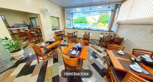 un ristorante con tavoli e sedie in legno e una grande finestra di Hotel Boa Vista a Americana