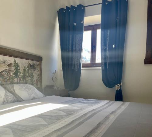 a bedroom with blue curtains and a bed and a window at Rifugio Baita Gimont in Cesana Torinese