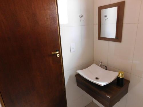 a bathroom with a sink and a wooden door at Chalés Viver a Mantiqueira in São Bento do Sapucaí