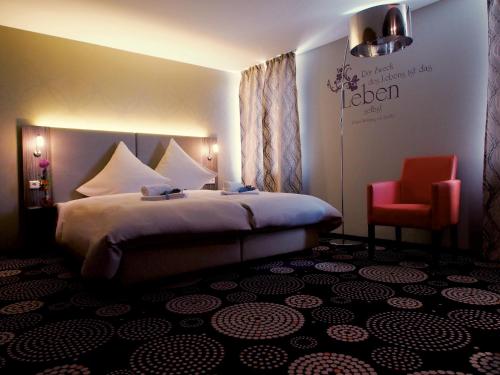 una camera d'albergo con letto e sedia rossa di Myhotel a Künzelsau