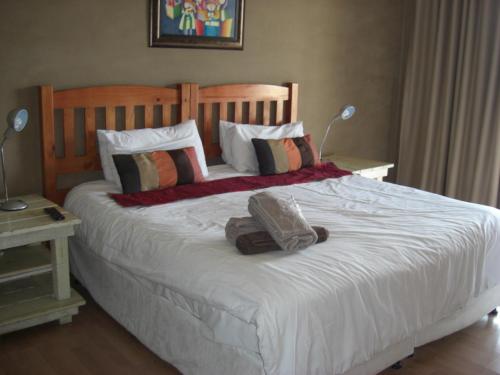 1 dormitorio con 1 cama blanca grande con almohadas en The Deck on Manning, en Durban